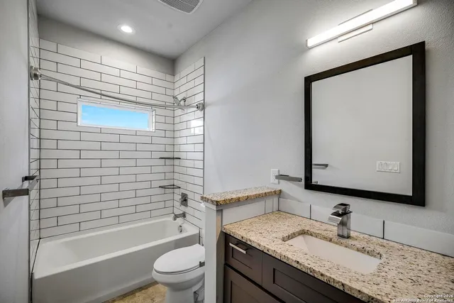 a bathroom with a granite countertop sink toilet and shower
