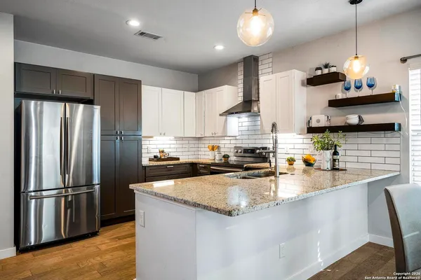 a kitchen with refrigerator a stove a center island and wooden floor