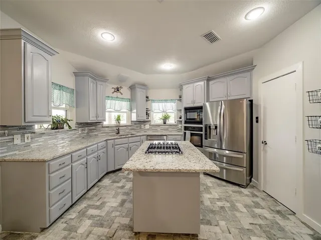 a kitchen with stainless steel appliances granite countertop a refrigerator a sink dishwasher a stove with wooden cabinets and a granite counter top