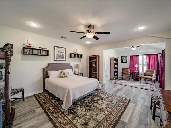 a bedroom with a large bed a flat tv screen and a dresser