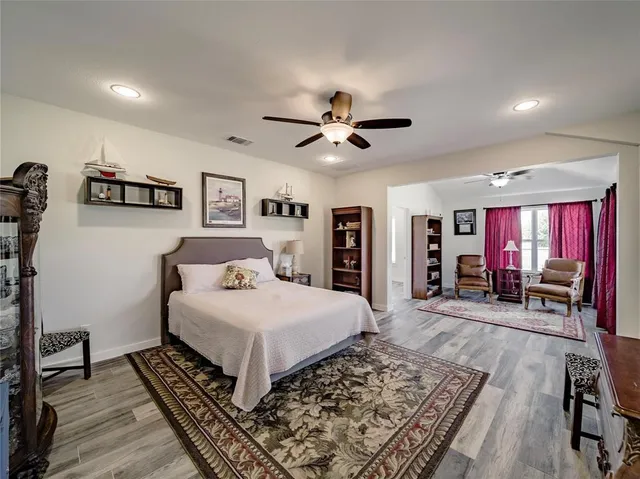 a bedroom with a large bed a flat tv screen and a dresser