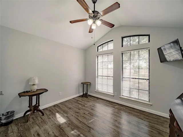a view of an empty room with a window and wooden floor