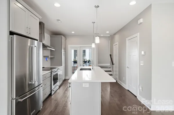 a large kitchen with a large window a refrigerator and stainless steel appliances
