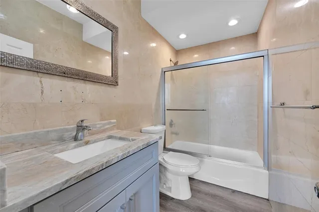 a bathroom with a granite countertop sink a toilet and shower