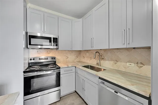 a kitchen with granite countertop white cabinets and stainless steel appliances