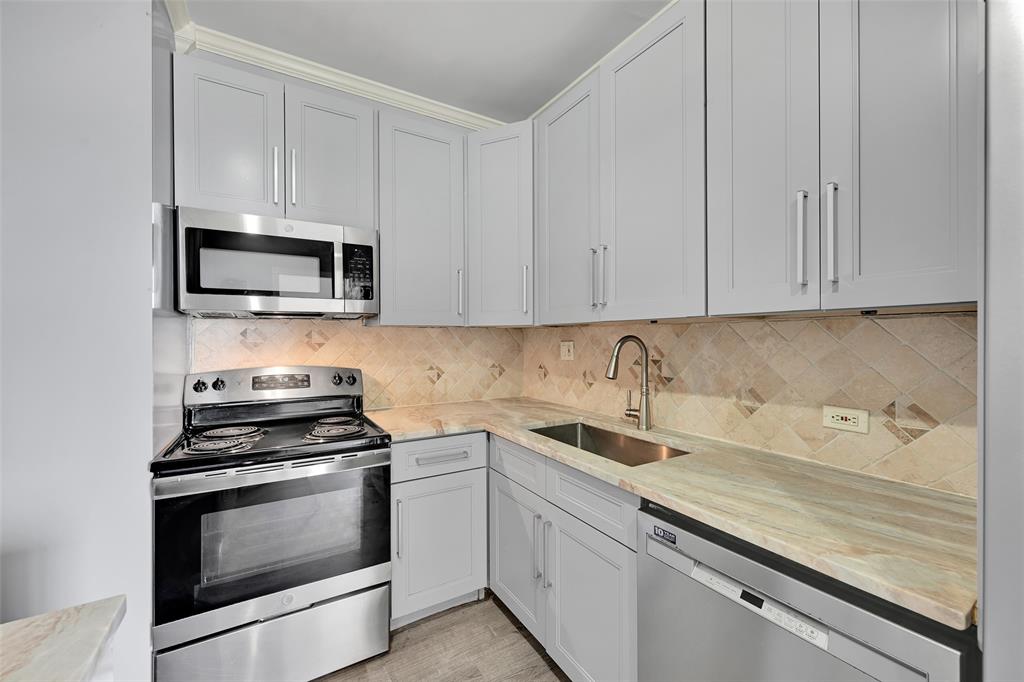 5005 Collins Avenue, Unit PH6 Miami Beach, FL 33140 - Photo 6 of 34 a kitchen with granite countertop white cabinets and stainless steel appliances