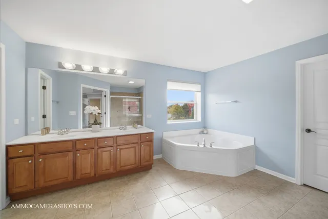 a spacious bathroom with a double vanity sink a mirror and a bathtub