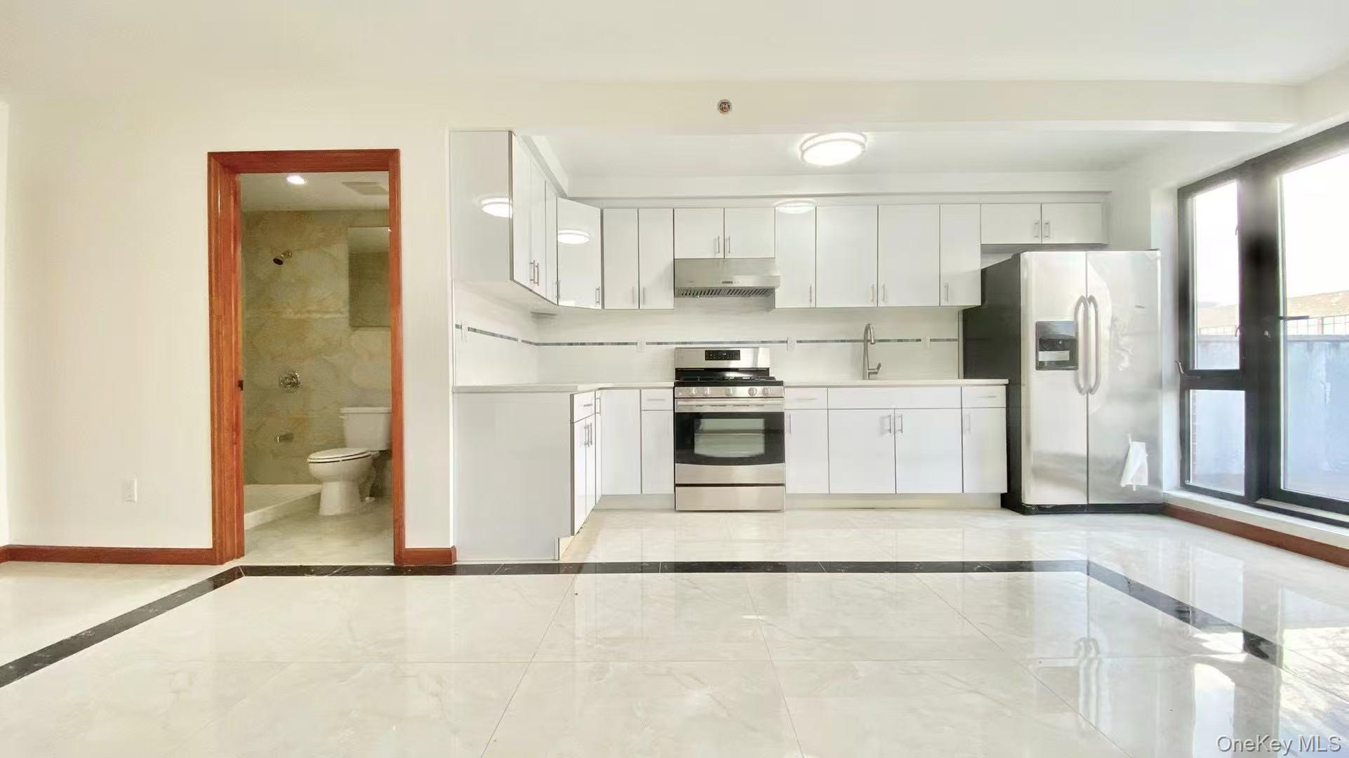 108-38 41st Avenue, Unit 4A Queens, NY 11368 - Photo 3 of 10 a kitchen with stainless steel appliances granite countertop a refrigerator a stove a sink and white cabinets with wooden floor
