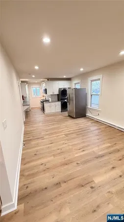 a kitchen with granite countertop a stove top oven a sink dishwasher and white cabinets with wooden floor