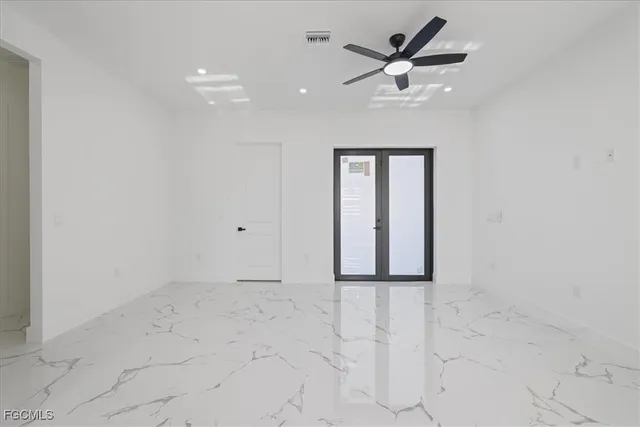 an empty room with ceiling fan and window