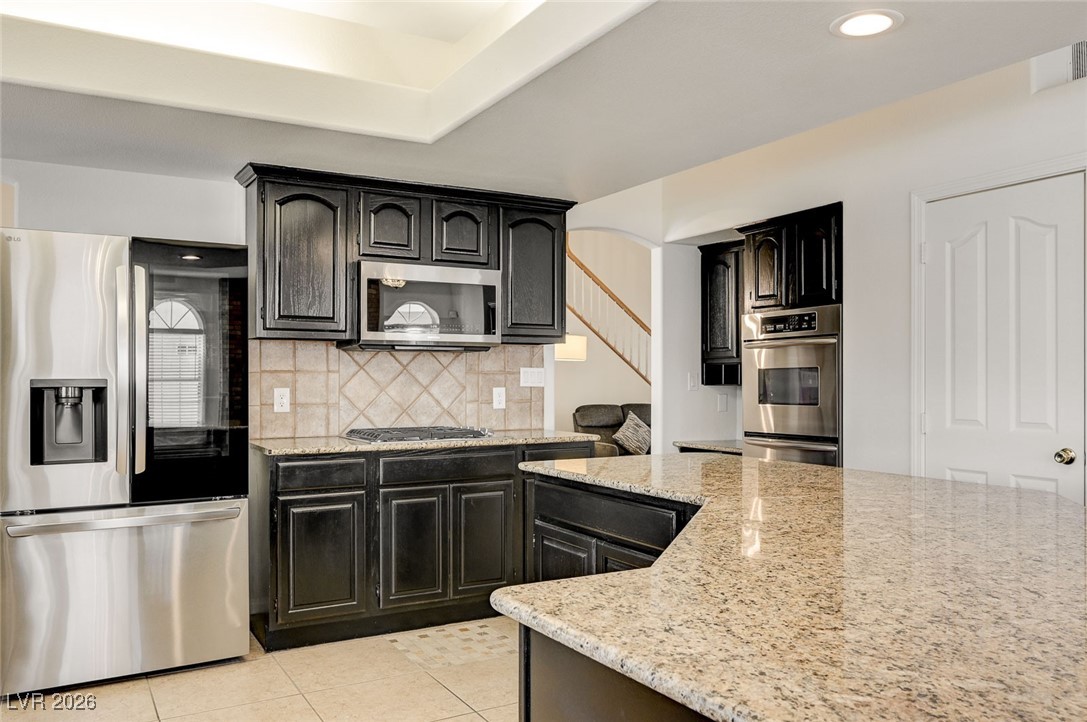 2955 El Camino Road Las Vegas, NV 89146 - Photo 25 of 99 Kitchen with appliances with stainless steel finishes, light stone counters, decorative backsplash, light tile patterned floors, and recessed lighting