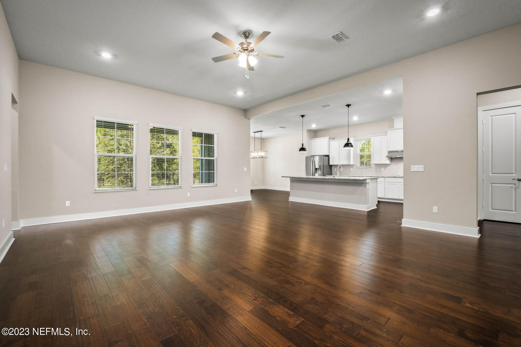 36426 Pitch Lane Hilliard, FL 32046 - Photo 4 of 14 an empty room with wooden floor and kitchen view
