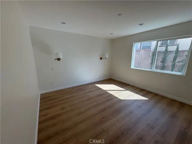 a view of an empty room with wooden floor and closet