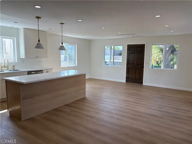 a kitchen with stainless steel appliances granite countertop a sink a stove and a wooden floor