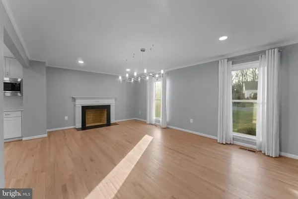 a large white kitchen with a large window a island wooden floor and stainless steel appliances