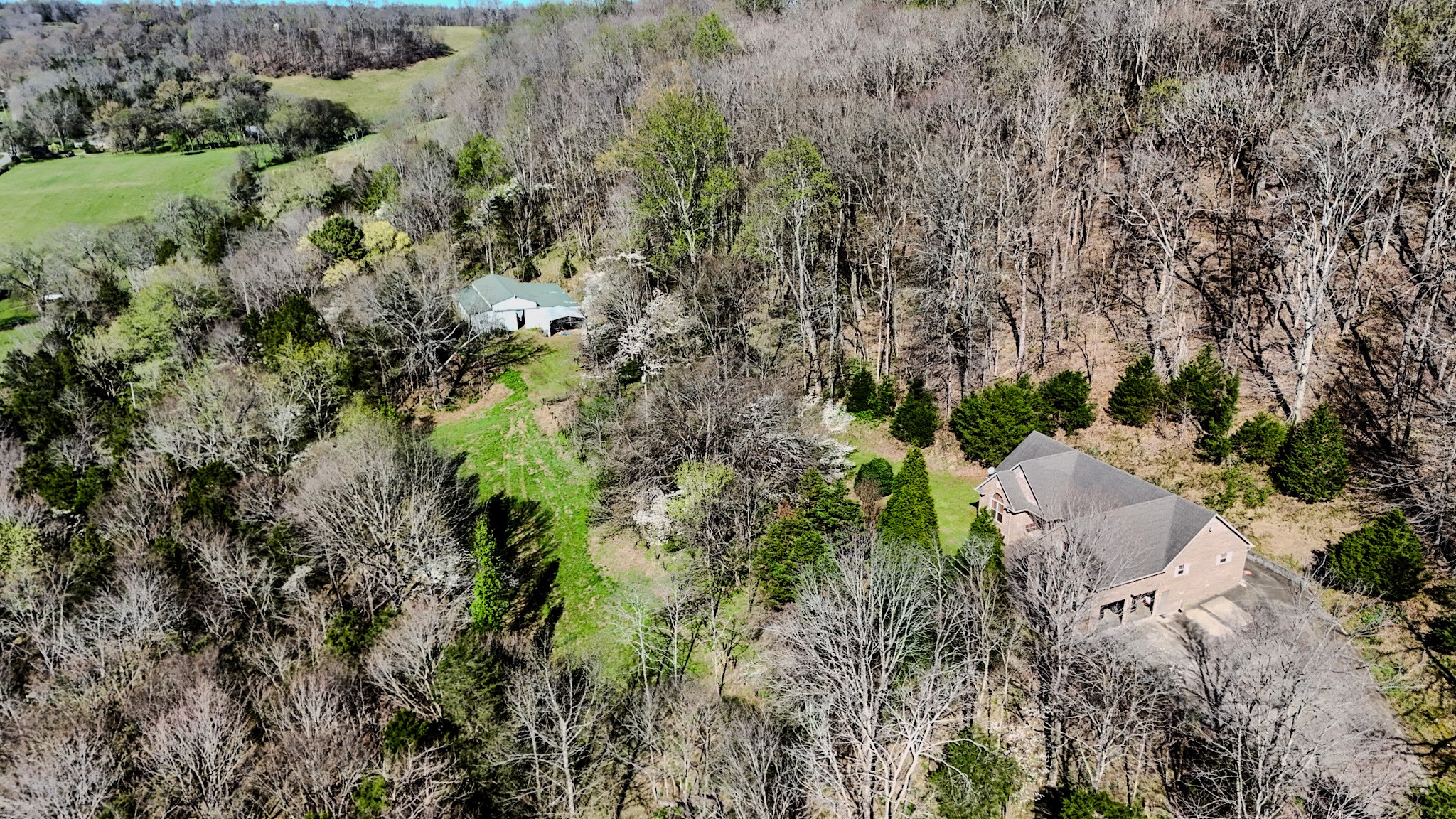 an aerial view of residential house with outdoor space and trees all around