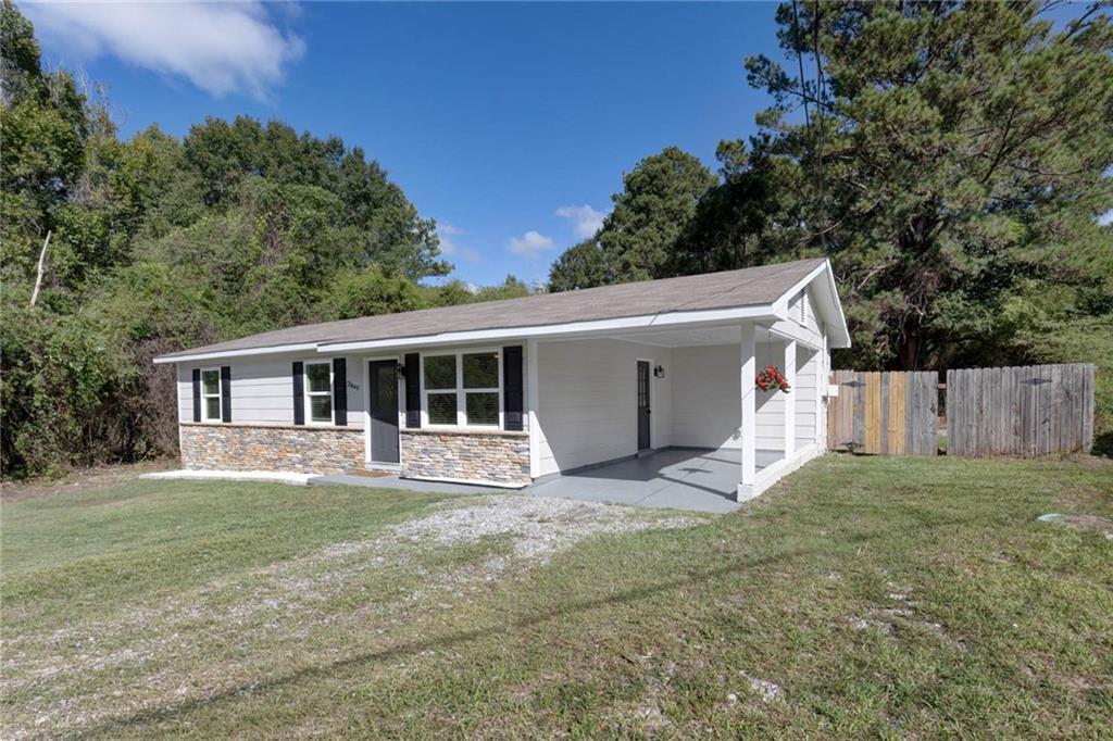 2899 Lamb Road Smiths Station, AL 36877 - Photo 3 of 26 Exterior with horizontal siding, stone veneer accents, dark shutters, a covered carport, and a wood privacy fence