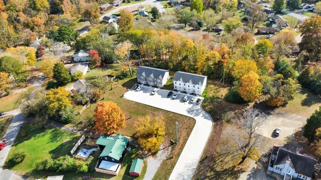 aerial view of a house with yard and trees in the background