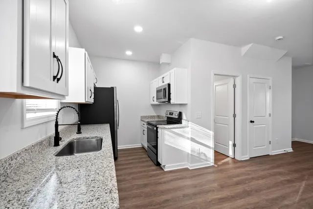 an empty room with wooden floor a ceiling fan and windows
