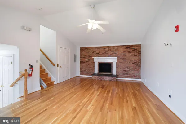 a view of a hallway with wooden floor and a bathroom