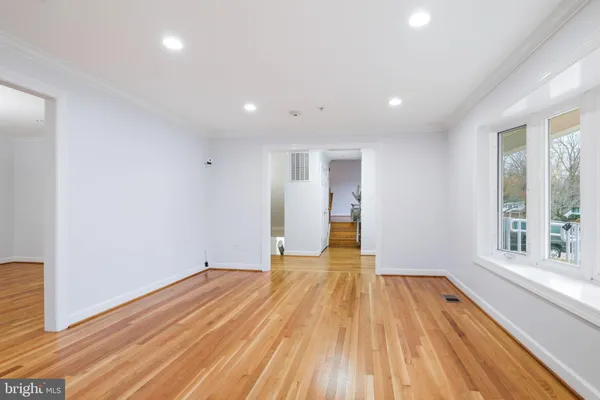 an empty room with wooden floor chandelier and windows
