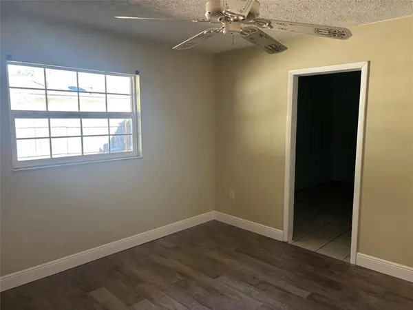 an empty room with wooden floor closet and windows