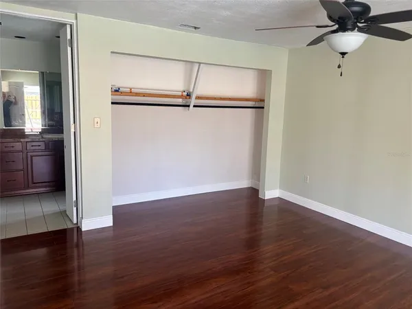 an empty room with wooden floor cabinet and windows