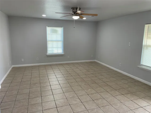 an empty room with windows and ceiling fan