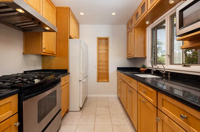 a kitchen with granite countertop cabinets stainless steel appliances a sink and wooden floor