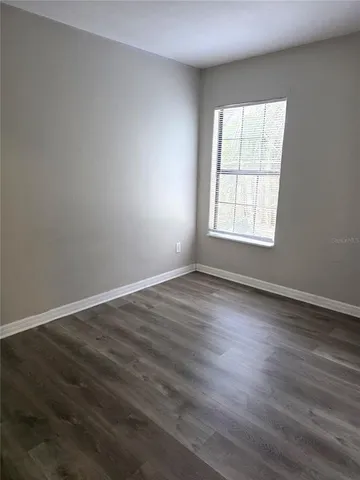 an empty room with wooden floor and window