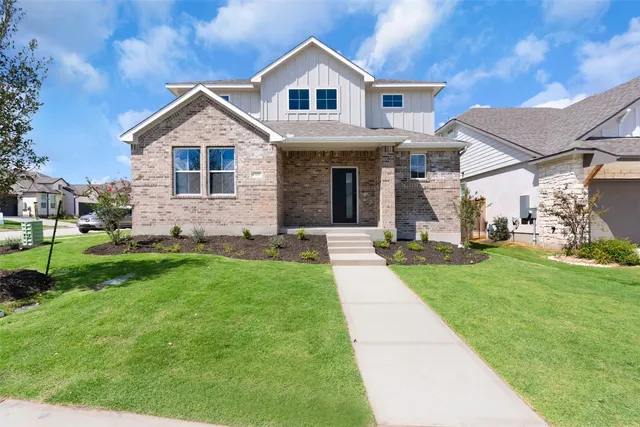 a front view of house with yard and trees in the background