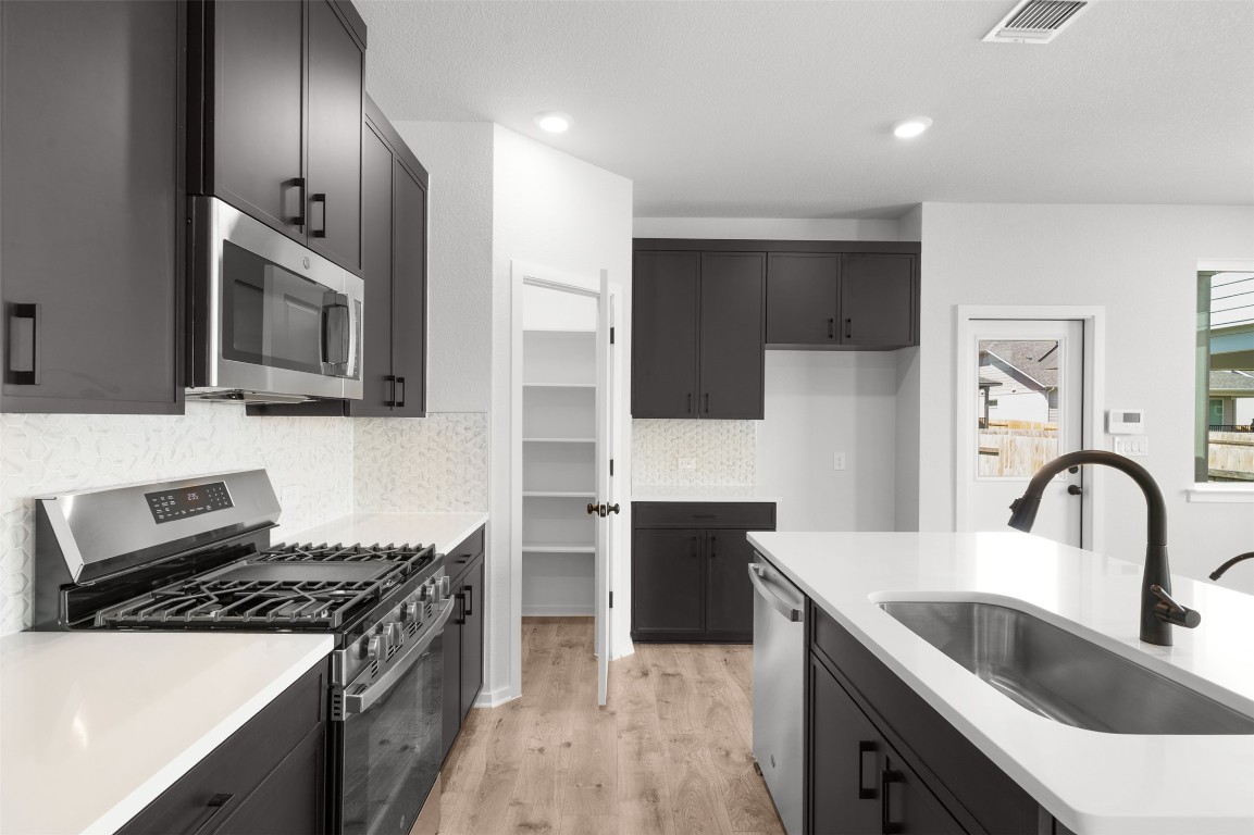 101 Coyote Willow Way Georgetown, TX 78633 - Photo 14 of 34 a kitchen with stainless steel appliances granite countertop a sink stove and refrigerator