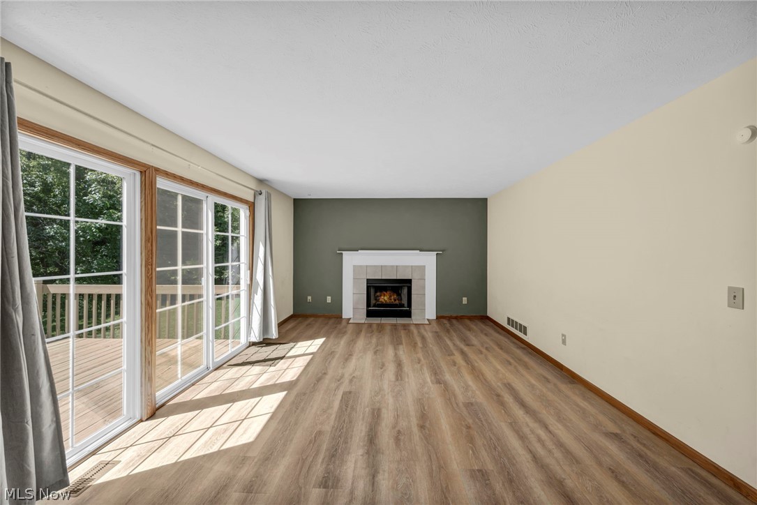 9842 Johnnycake Ridge Road Mentor, OH 44060 - Photo 14 of 40 Spacious room featuring wood-finish flooring, a white mantel fireplace with tile surround, and an accent wall