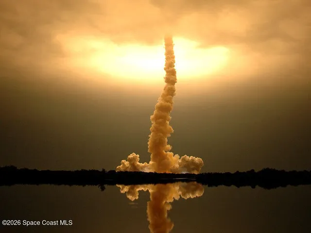 a front view of a building with glass windows and iron fence