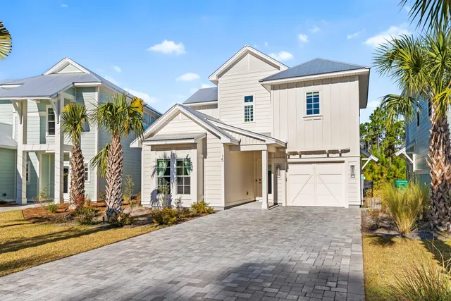 a view of a white house with a small yard and plants