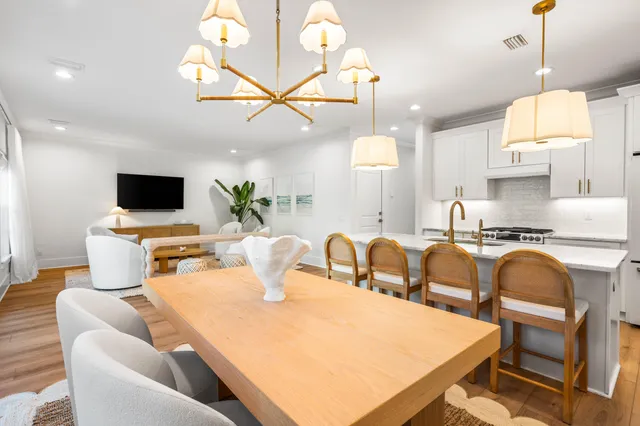 a kitchen with stainless steel appliances kitchen island granite countertop a sink a stove a dining table and chairs