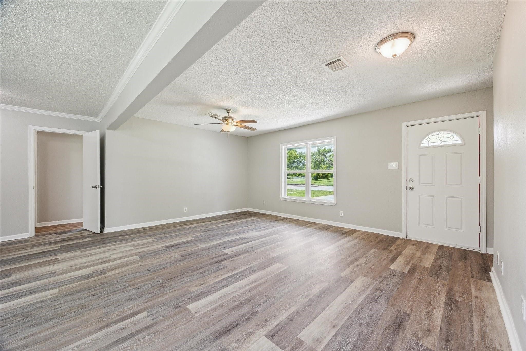 210 Laurel Street Lake Jackson, TX 77566 - Photo 2 of 13 wooden floor in an empty room with a window