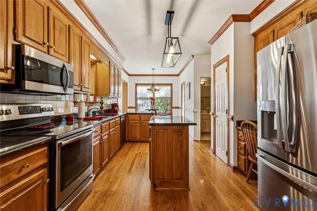 a kitchen with stainless steel appliances granite countertop a refrigerator a stove and a wooden floors
