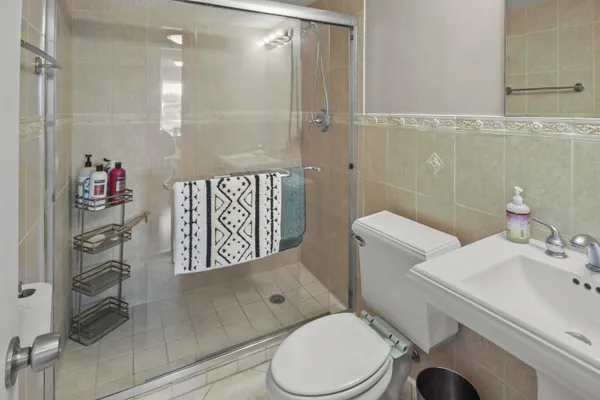 a view of a hallway with wooden floor and a bathroom