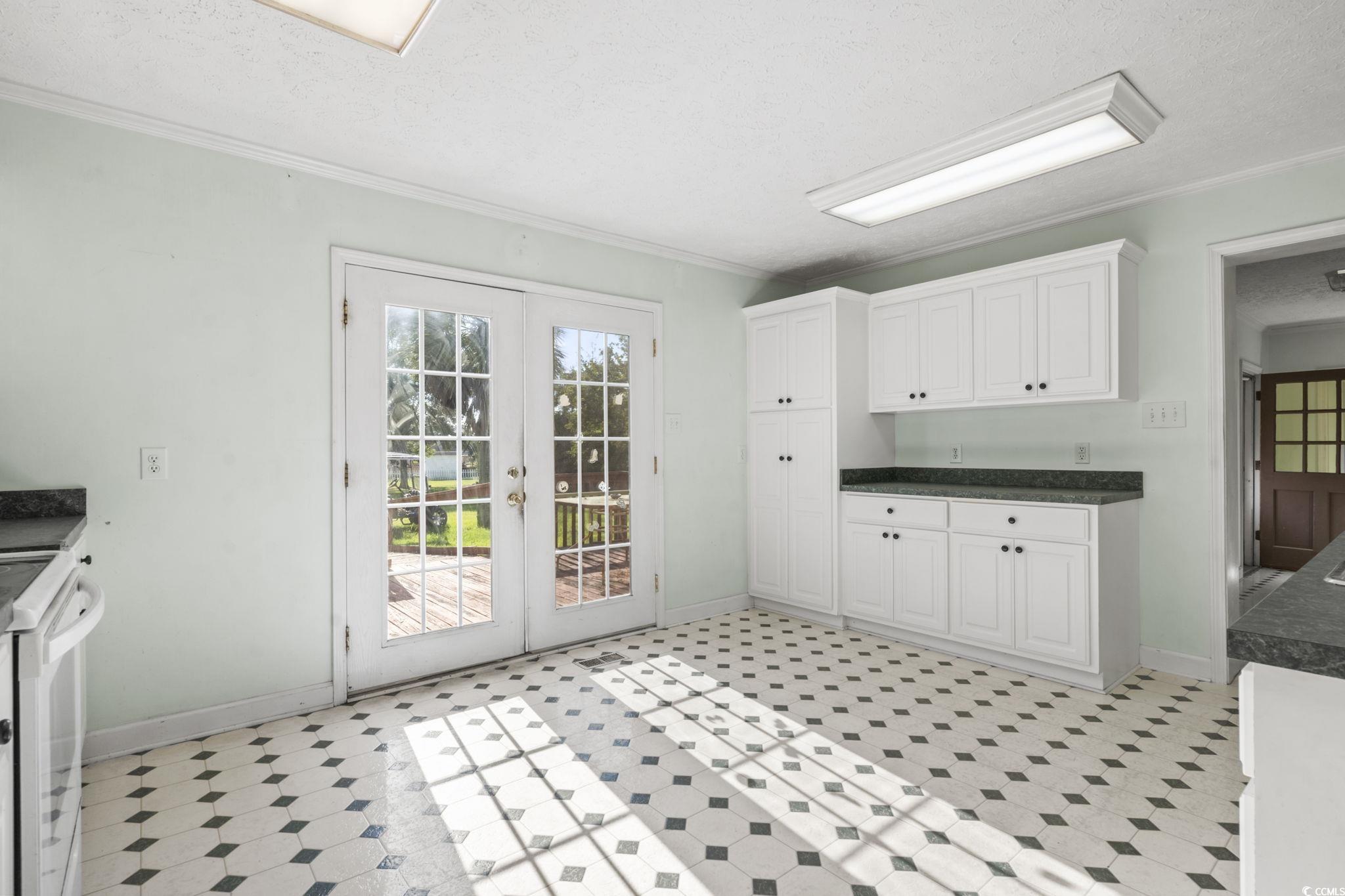 6971 Alfred Road Aynor, SC 29511 - Photo 14 of 37 Kitchen featuring a textured ceiling, french doors, dark countertops, ornamental molding, and white cabinets