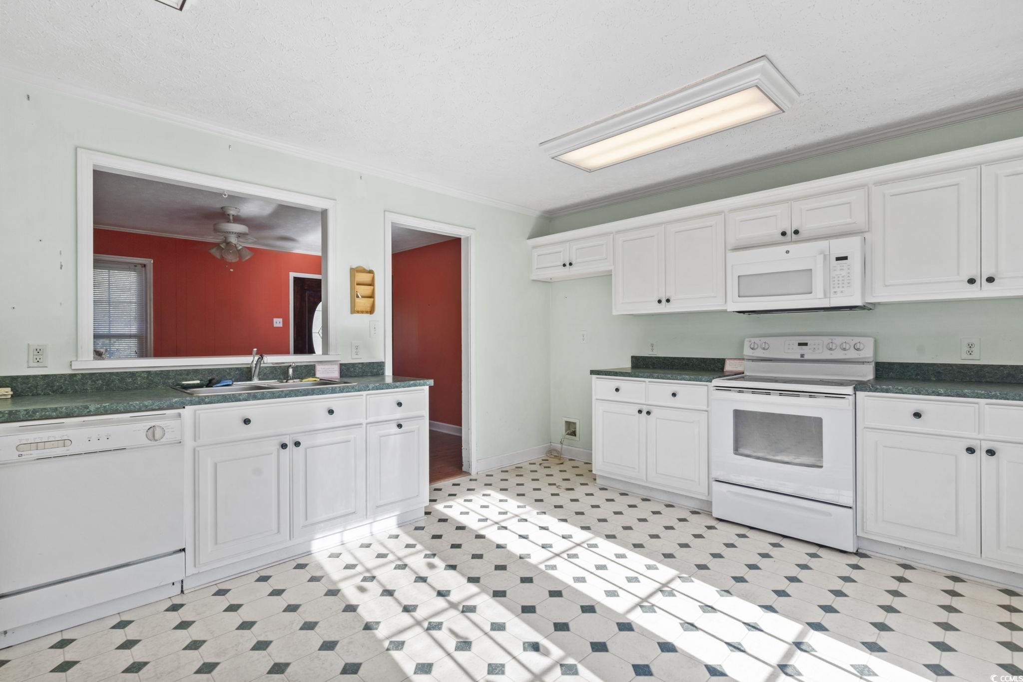 6971 Alfred Road Aynor, SC 29511 - Photo 15 of 37 Kitchen with white appliances, dark countertops, white cabinetry, ornamental molding, and light flooring