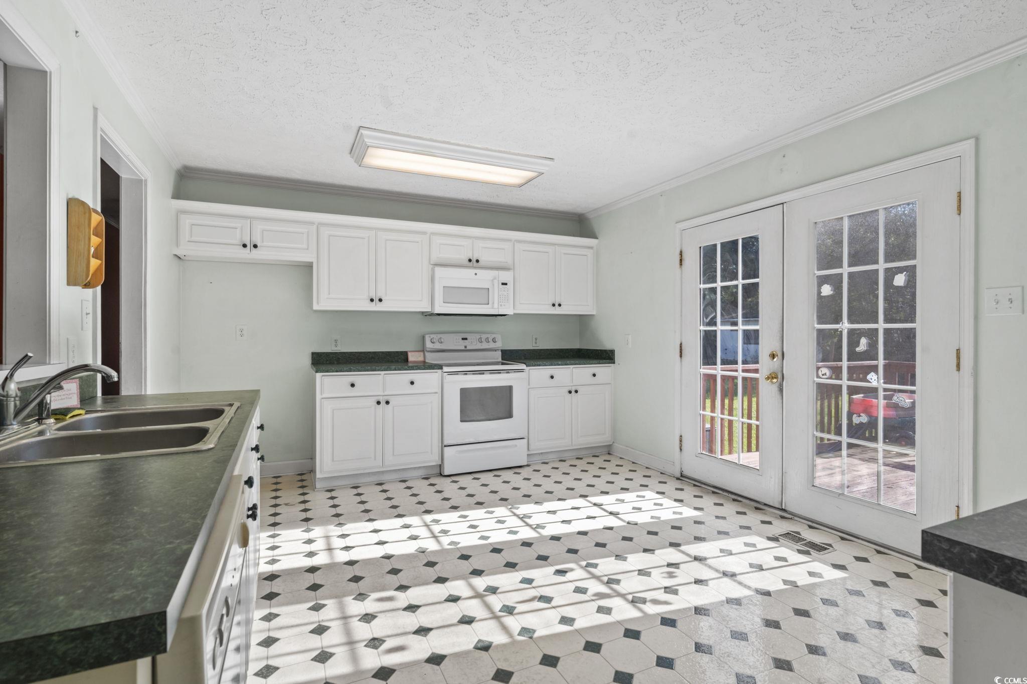 6971 Alfred Road Aynor, SC 29511 - Photo 16 of 37 Kitchen featuring french doors, dark countertops, white appliances, crown molding, and a textured ceiling