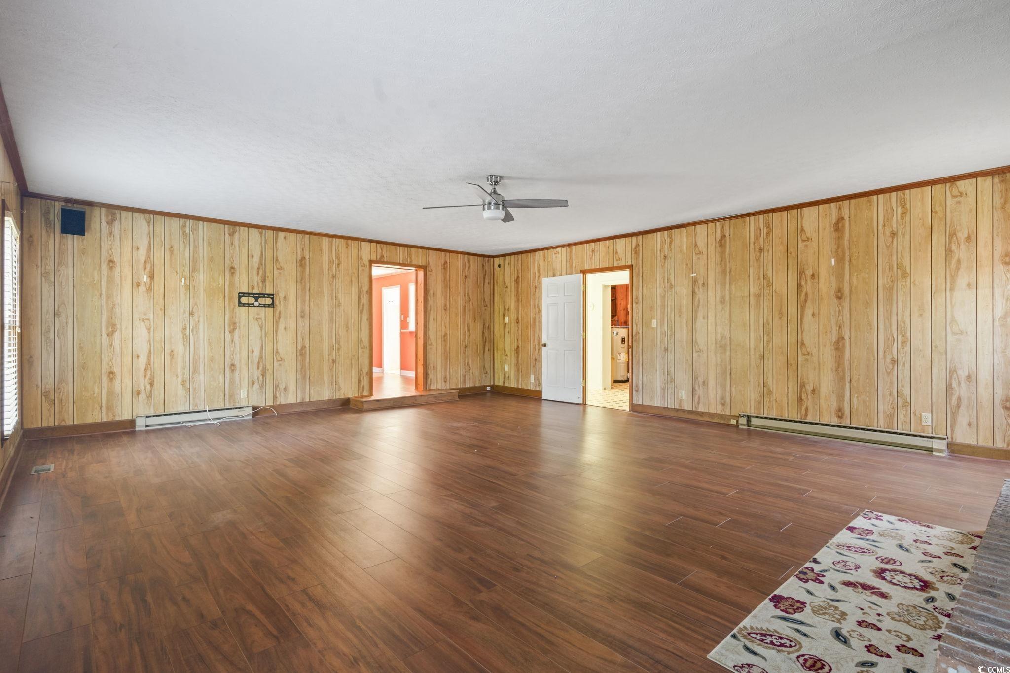 6971 Alfred Road Aynor, SC 29511 - Photo 8 of 37 Unfurnished living room with dark wood-type flooring, baseboard heating, crown molding, a baseboard heating unit, and ceiling fan