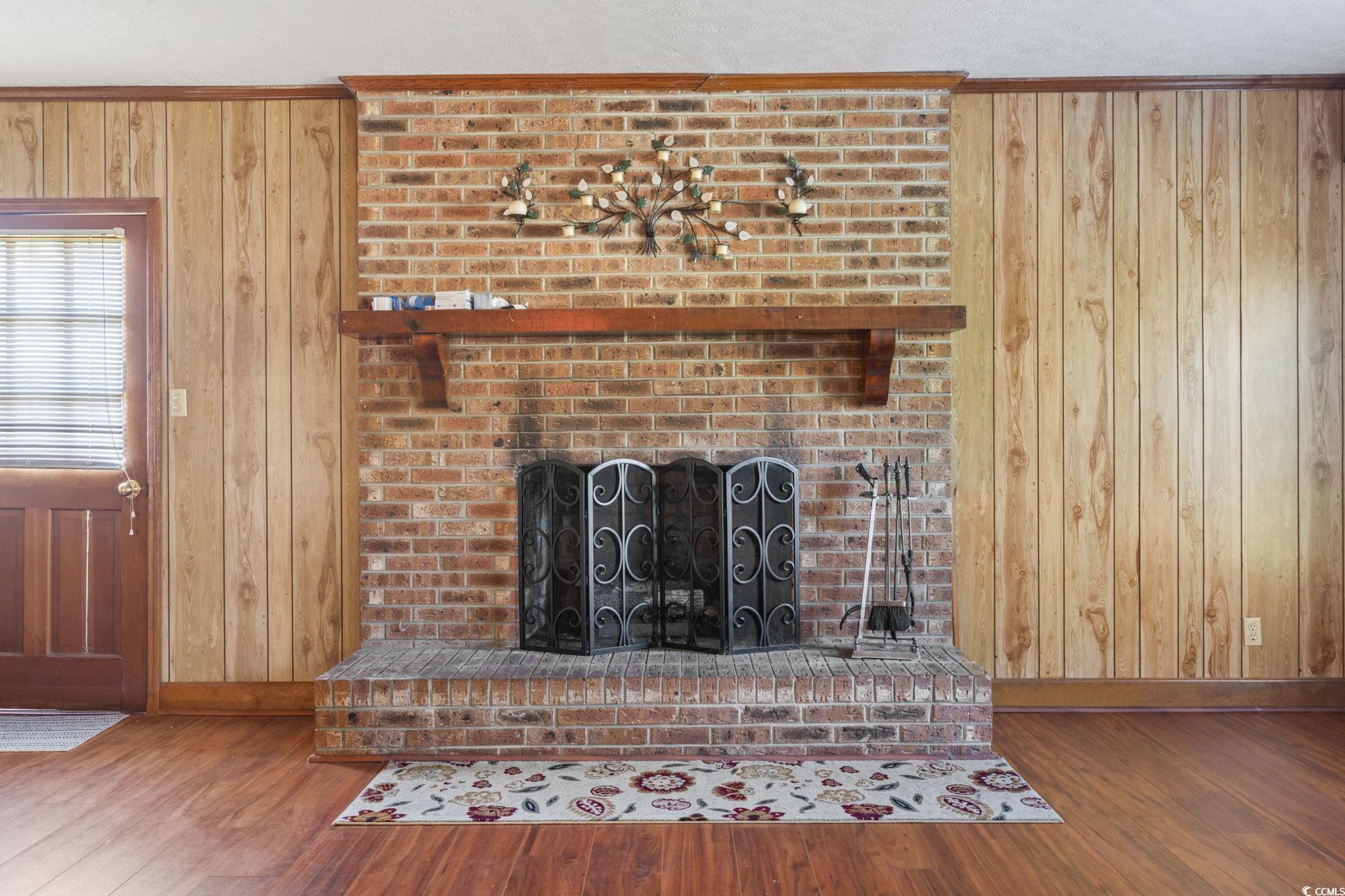 6971 Alfred Road Aynor, SC 29511 - Photo 10 of 37 Detailed view of wood walls, a brick fireplace, and wood finished floors