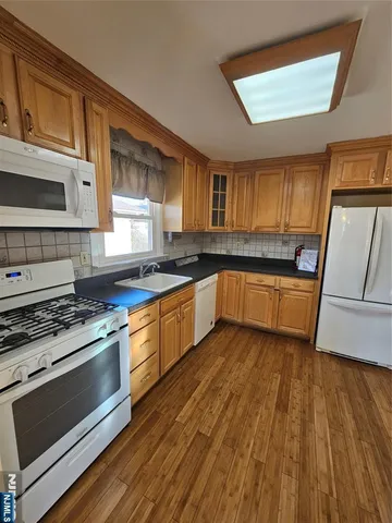 a kitchen with granite countertop wooden floors a stove and a microwave