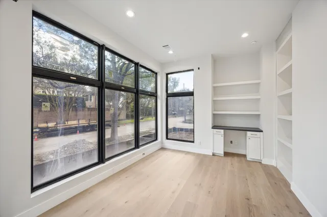 a view of a hallway to room with wooden floor and windows