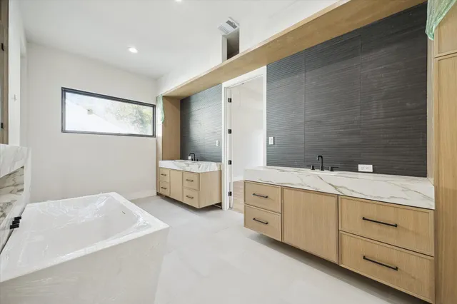 a bathroom with double vanity sink a mirror and a bathtub
