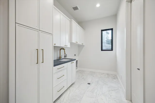 a kitchen with white cabinets and sink