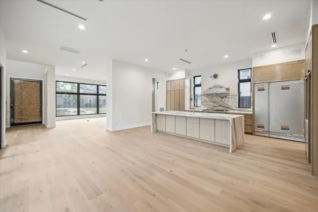 a view of kitchen with kitchen island granite countertop wooden cabinets and refrigerator
