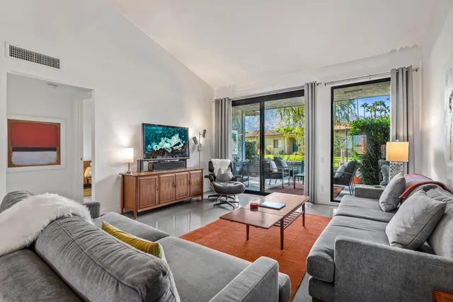 a living room with furniture a flat screen tv and a floor to ceiling window
